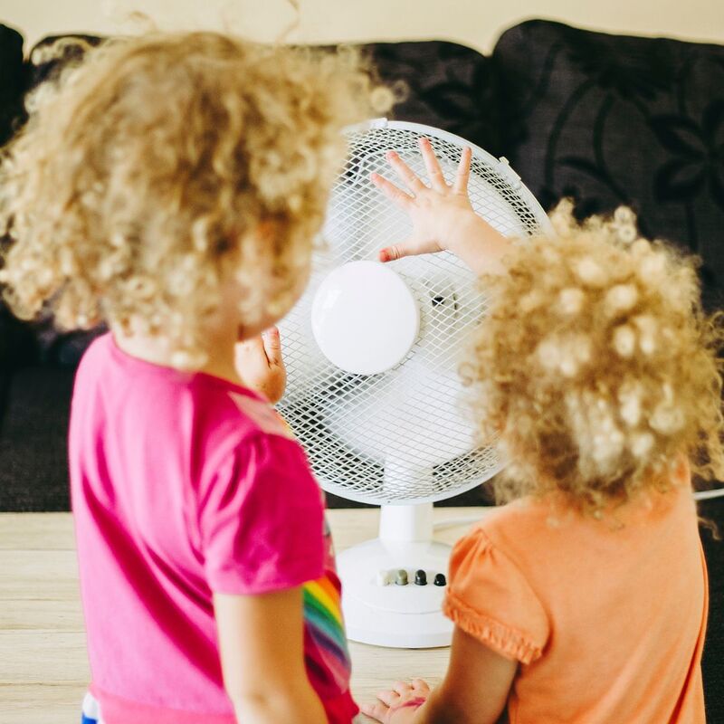 Photo of children sitting in front of a fan.